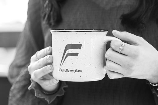 Lady holding a First Metro Bank coffee mug