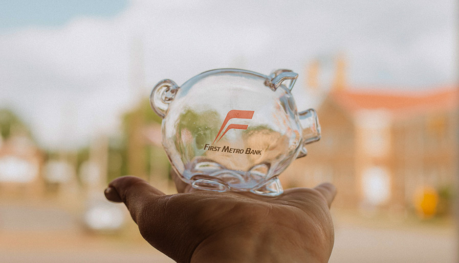 A lady holding a First Metro Bank piggy bank