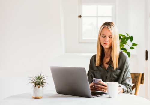 woman working in white room on laptop and cellphone